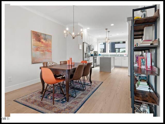 dining area with ornamental molding, sink, a chandelier, and light hardwood / wood-style flooring