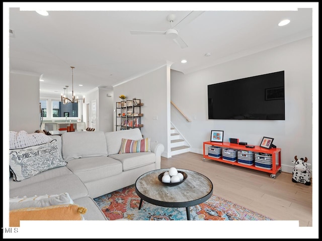 living room featuring ornamental molding, ceiling fan with notable chandelier, and hardwood / wood-style floors