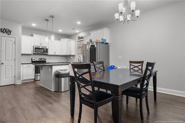 dining area featuring dark hardwood / wood-style flooring, a notable chandelier, and sink