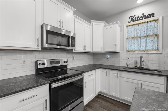 kitchen featuring sink, stainless steel appliances, dark stone counters, and white cabinets