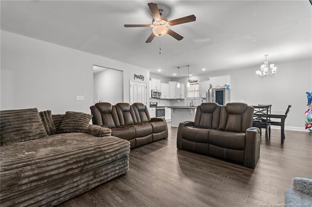 living room featuring dark hardwood / wood-style flooring and ceiling fan with notable chandelier