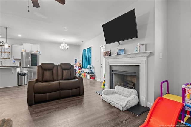 living room featuring dark hardwood / wood-style flooring and ceiling fan with notable chandelier