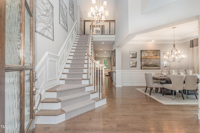 foyer entrance with a high ceiling, ornamental molding, hardwood / wood-style floors, and an inviting chandelier