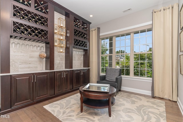 sitting room with light hardwood / wood-style flooring and bar area