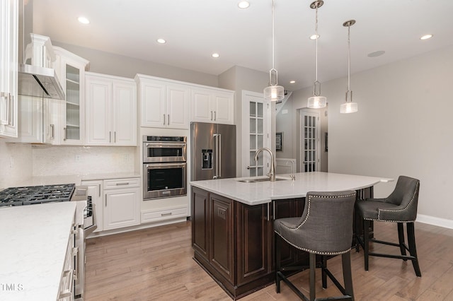 kitchen featuring sink, decorative light fixtures, an island with sink, stainless steel appliances, and decorative backsplash