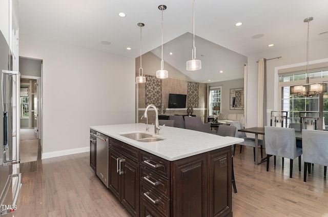 kitchen featuring sink, dishwasher, a kitchen island with sink, dark brown cabinets, and decorative light fixtures