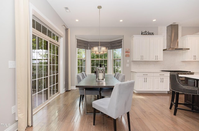 dining area featuring light hardwood / wood-style flooring, a wealth of natural light, and an inviting chandelier