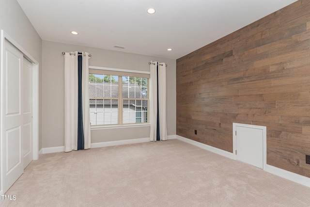 carpeted spare room with wooden walls