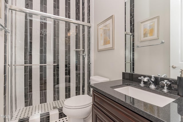 bathroom featuring vanity, a tile shower, and toilet