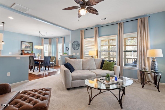 living area with light carpet, ceiling fan, and visible vents