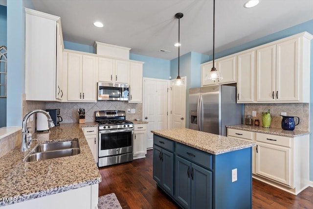 kitchen featuring a center island, decorative light fixtures, stainless steel appliances, blue cabinetry, and a sink