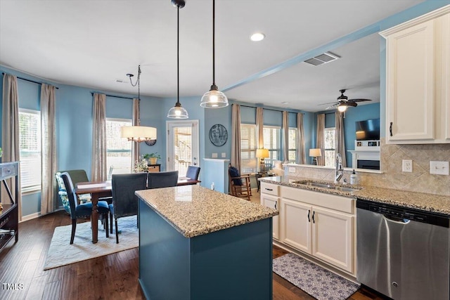 kitchen featuring visible vents, hanging light fixtures, a kitchen island, light stone countertops, and dishwasher