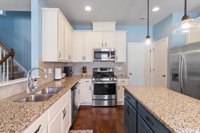 kitchen featuring blue cabinets, a sink, white cabinetry, appliances with stainless steel finishes, and pendant lighting