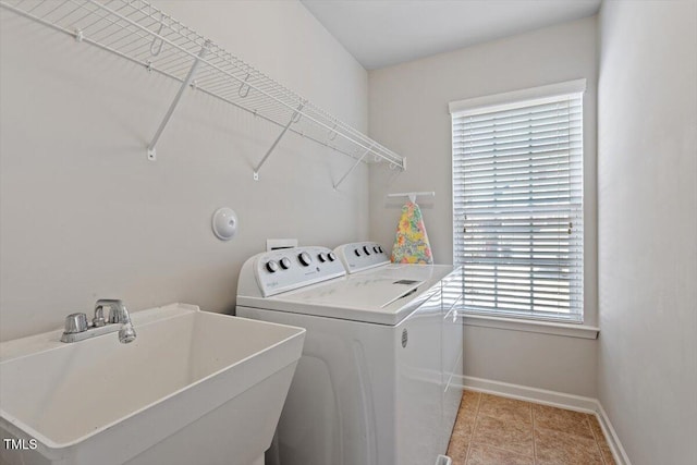 laundry area featuring light tile patterned flooring, laundry area, a sink, baseboards, and washing machine and clothes dryer