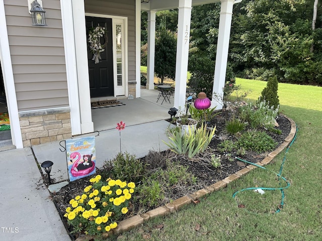 property entrance featuring a porch, stone siding, and a lawn