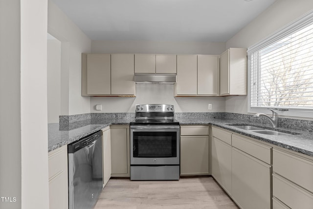 kitchen featuring sink, light wood-type flooring, stone counters, stainless steel appliances, and cream cabinetry