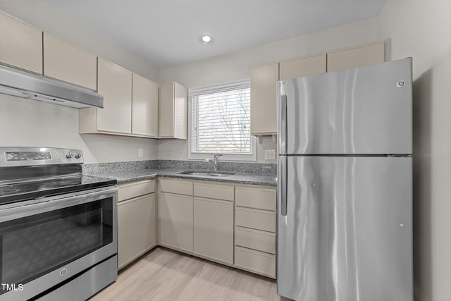 kitchen with appliances with stainless steel finishes, sink, light hardwood / wood-style floors, and cream cabinetry