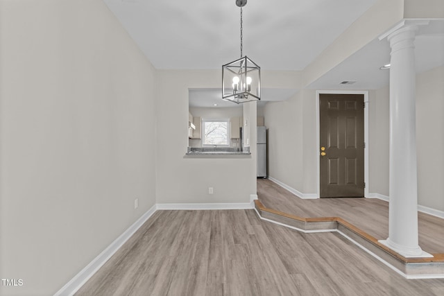 unfurnished dining area with ornate columns and light hardwood / wood-style floors