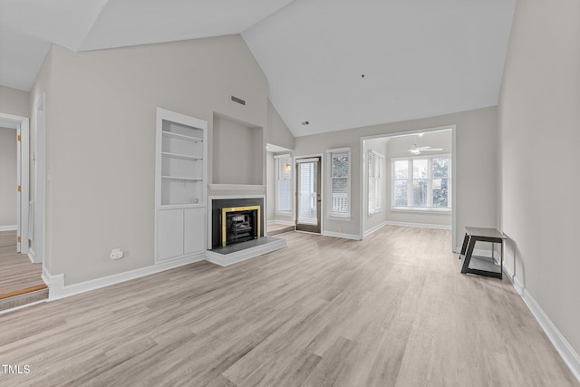 unfurnished living room with built in shelves, high vaulted ceiling, and light hardwood / wood-style floors