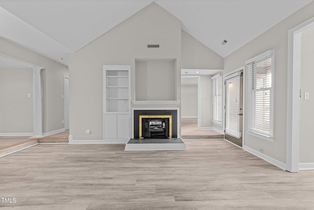 unfurnished living room featuring decorative columns, high vaulted ceiling, light wood-type flooring, and built in shelves