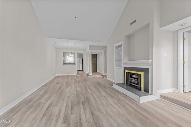 unfurnished living room featuring built in shelves, high vaulted ceiling, and light wood-type flooring