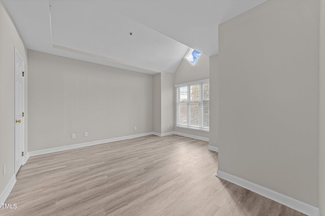 spare room with lofted ceiling with skylight and light hardwood / wood-style floors