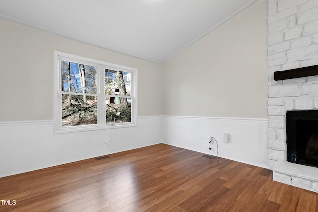 unfurnished living room featuring a stone fireplace, vaulted ceiling, and hardwood / wood-style flooring