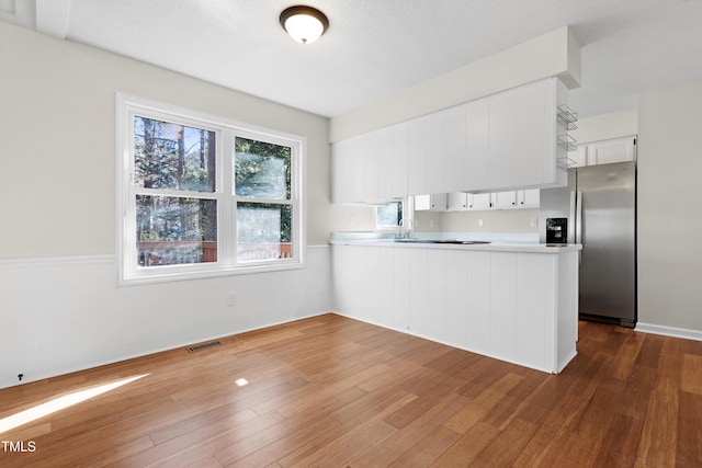 kitchen featuring white cabinetry, stainless steel fridge with ice dispenser, dark hardwood / wood-style flooring, and kitchen peninsula