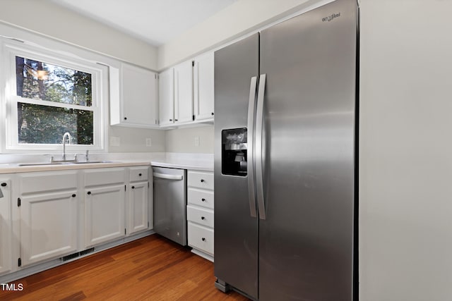 kitchen featuring appliances with stainless steel finishes, sink, dark wood-type flooring, and white cabinets