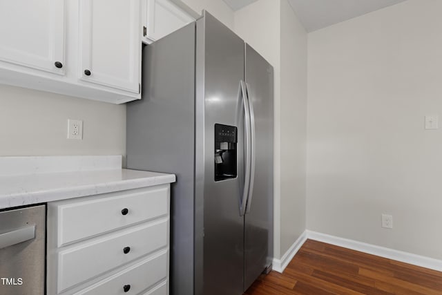 kitchen featuring stainless steel appliances, white cabinetry, dark wood-type flooring, and light stone counters