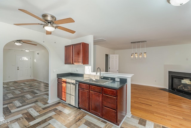 kitchen featuring sink, hanging light fixtures, wood-type flooring, stainless steel dishwasher, and kitchen peninsula