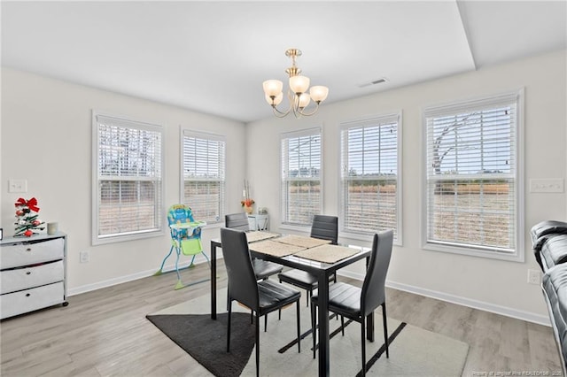 dining area with a healthy amount of sunlight, light wood-type flooring, and a notable chandelier