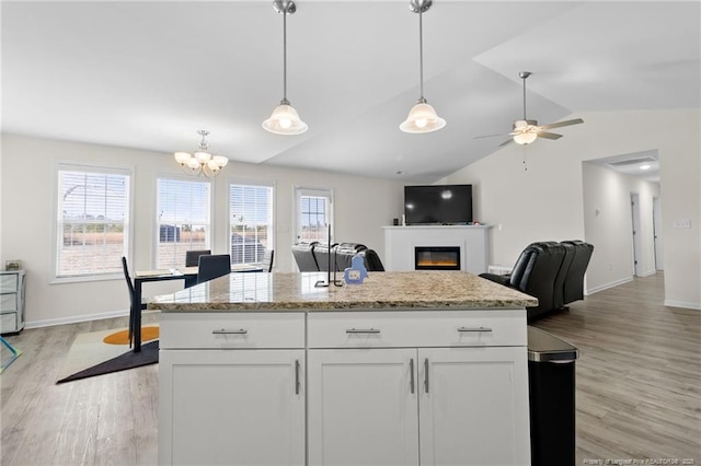 kitchen with white cabinetry, pendant lighting, light hardwood / wood-style flooring, and light stone countertops