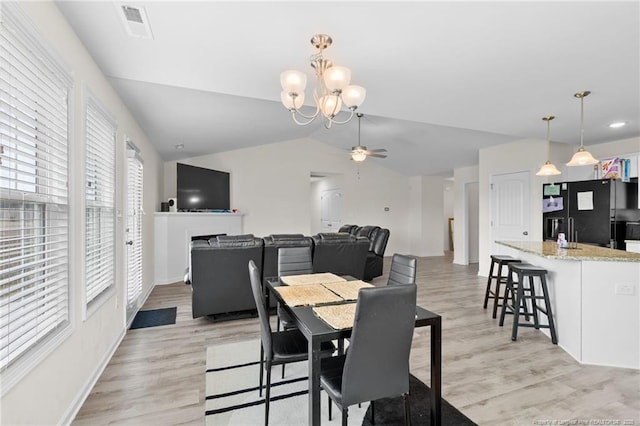 dining room featuring light hardwood / wood-style flooring, ceiling fan with notable chandelier, and vaulted ceiling