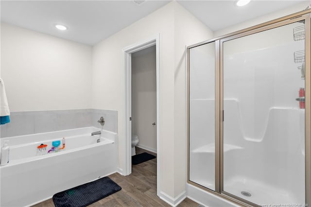 bathroom with wood-type flooring, separate shower and tub, and toilet