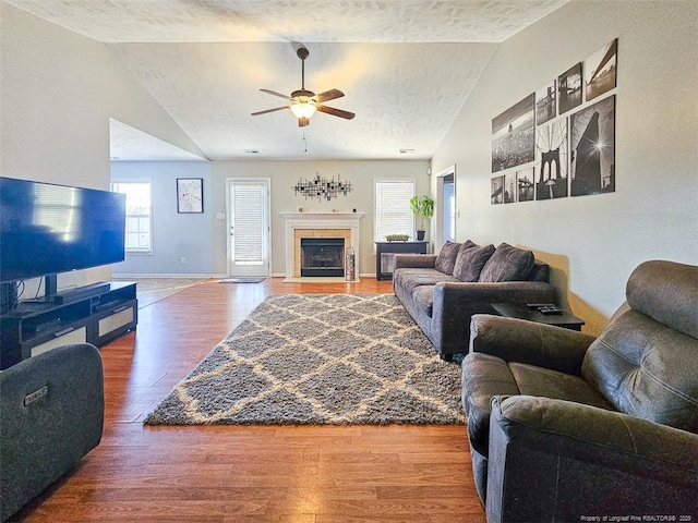 living room featuring vaulted ceiling, wood-type flooring, ceiling fan, and a textured ceiling