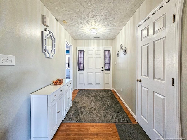 entryway with dark wood-type flooring and a textured ceiling