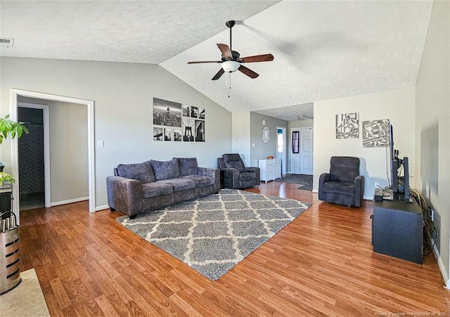 living room with ceiling fan, wood-type flooring, vaulted ceiling, and a textured ceiling