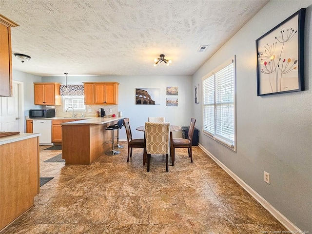 dining room featuring a healthy amount of sunlight, sink, and a textured ceiling