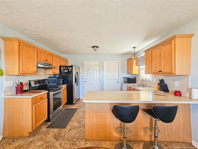 kitchen featuring pendant lighting, sink, stainless steel appliances, a kitchen bar, and kitchen peninsula