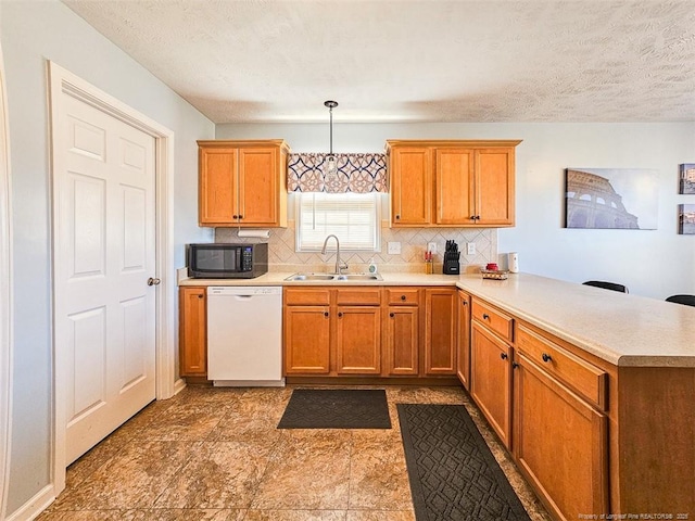 kitchen featuring pendant lighting, dishwasher, sink, backsplash, and kitchen peninsula