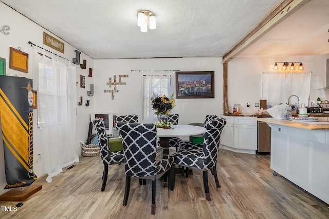 dining area with a textured ceiling and light wood-type flooring