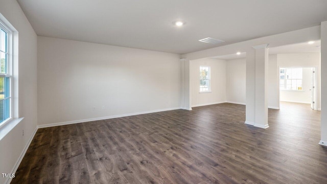 unfurnished room with decorative columns and dark wood-type flooring