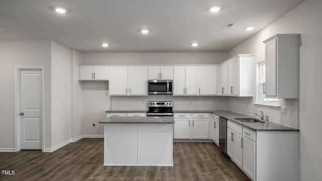 kitchen with stainless steel appliances, a kitchen island, sink, and white cabinets