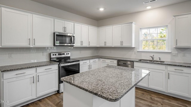 kitchen featuring appliances with stainless steel finishes, sink, a kitchen island, and white cabinets