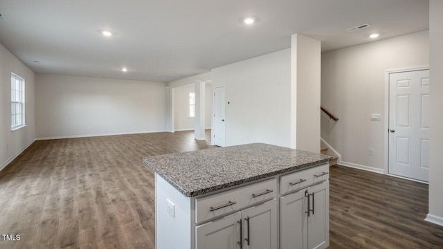 kitchen with white cabinetry, hardwood / wood-style flooring, light stone countertops, and a center island