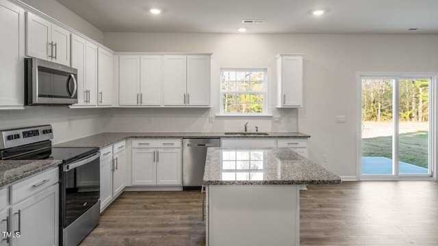 kitchen with a kitchen island, appliances with stainless steel finishes, sink, and white cabinets