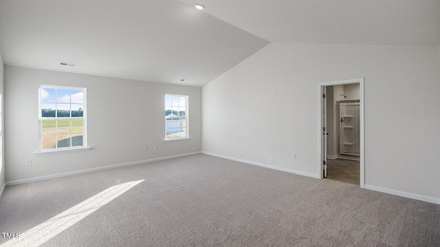 carpeted spare room featuring vaulted ceiling