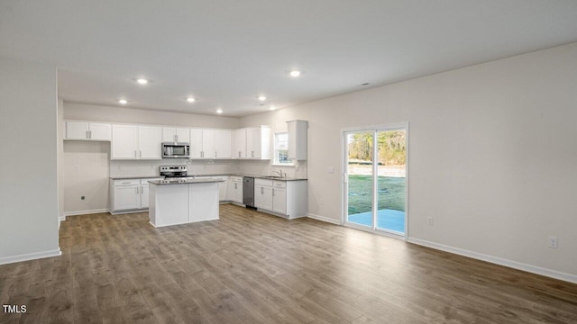 kitchen featuring appliances with stainless steel finishes, white cabinetry, decorative backsplash, a center island, and light hardwood / wood-style floors