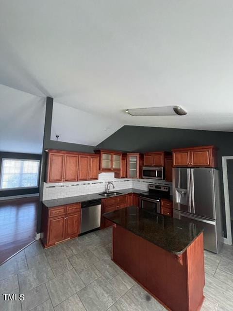 kitchen featuring lofted ceiling, sink, appliances with stainless steel finishes, backsplash, and a kitchen island